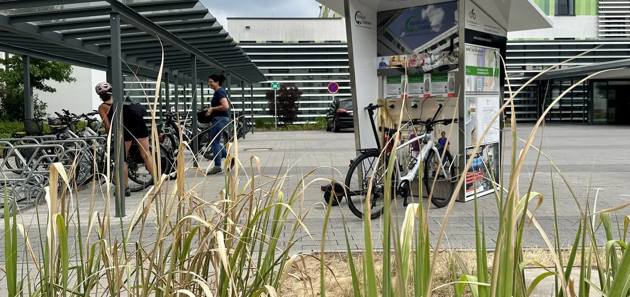 Überdachte E-Bike-Ladestationen mit Fahrrädern vor einem Firmengebäude